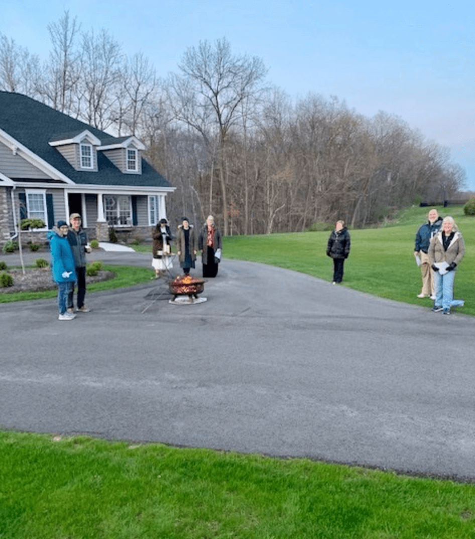 People standing outside social distancing around a fire
