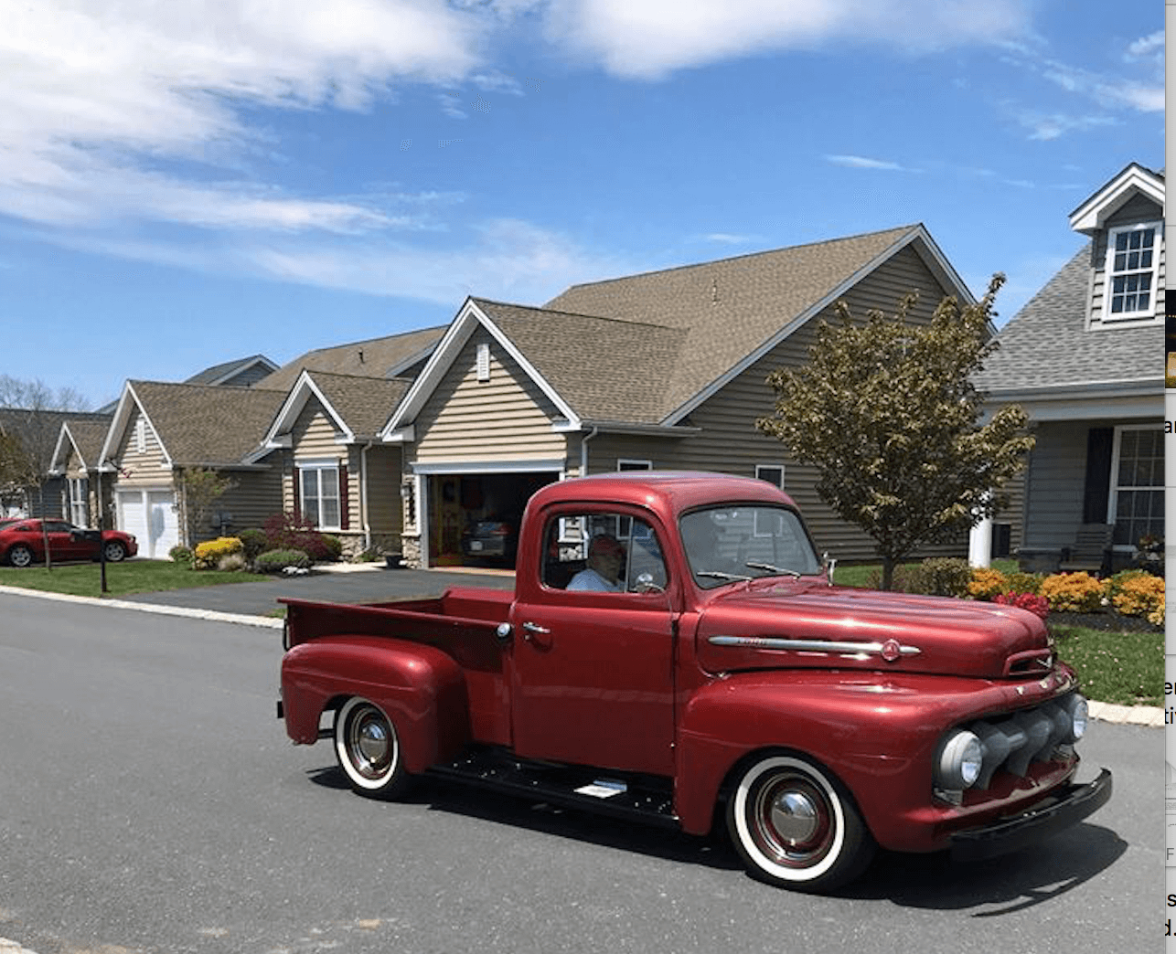 Red old time truck driving down the street of a Traditions of America community