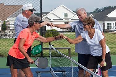 People fist-bumping over a pickle ball net from traditions of America