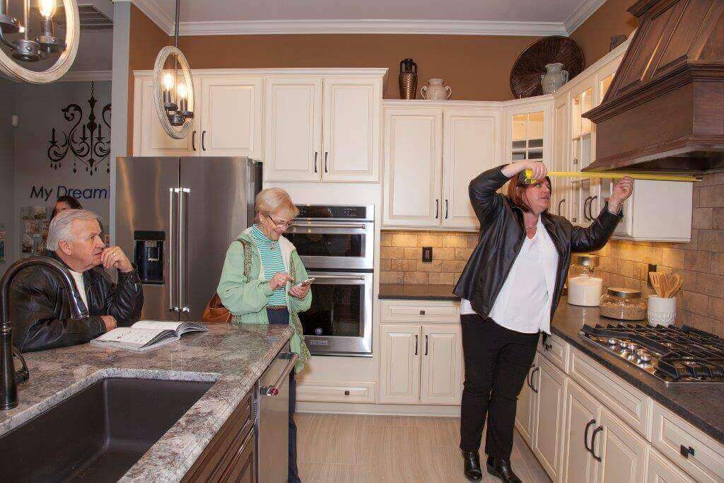 People measuring things in the kitchen of a Traditions of America open house