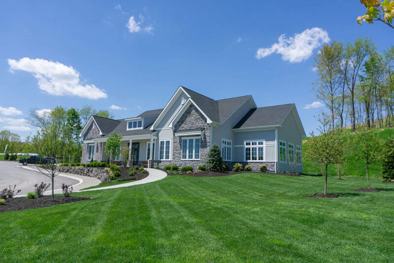 Cranberry Clubhouse With grey siding and Stone accents and a freshly mowed lawn