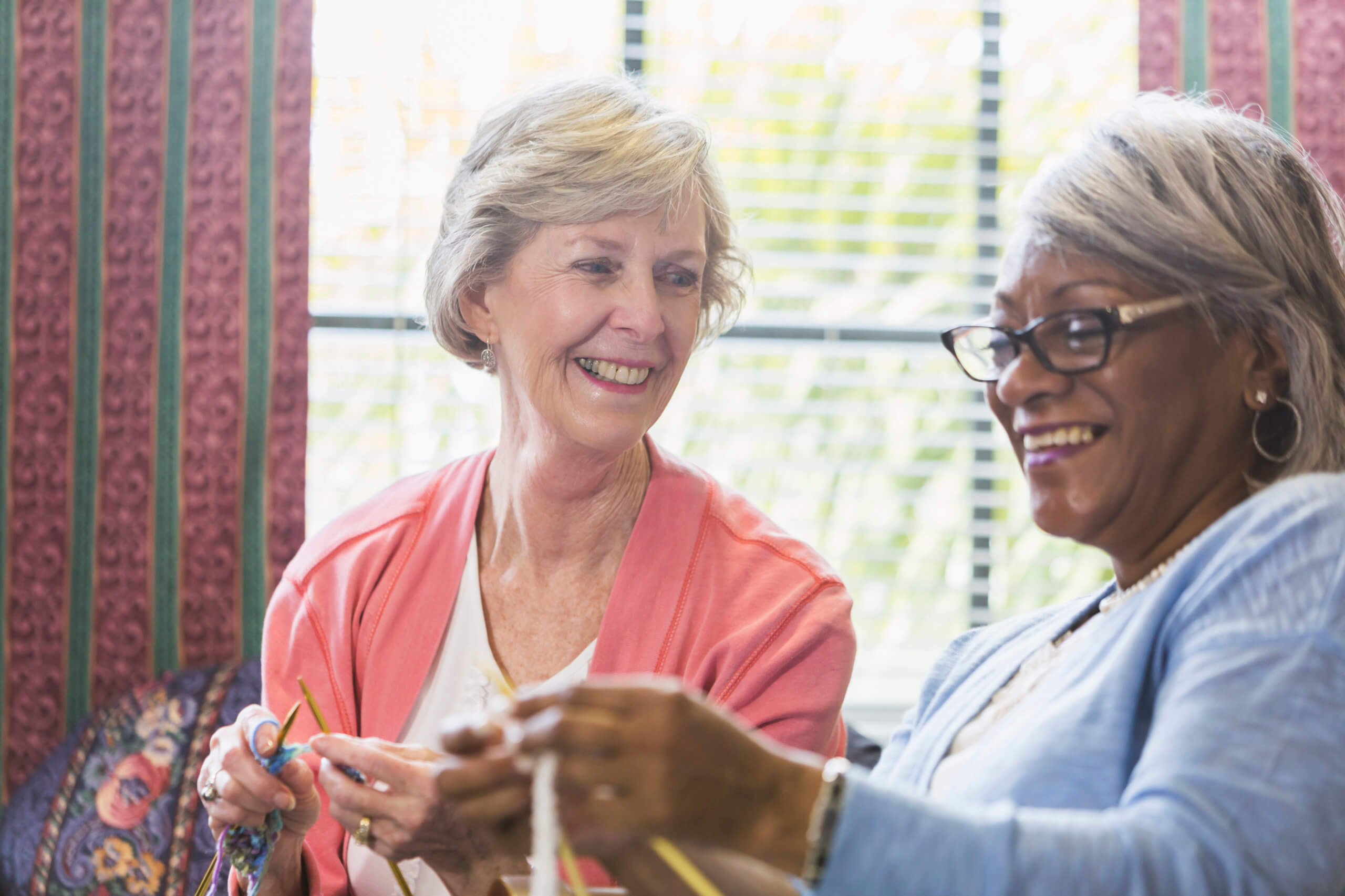 Senior woman knitting with African American friend