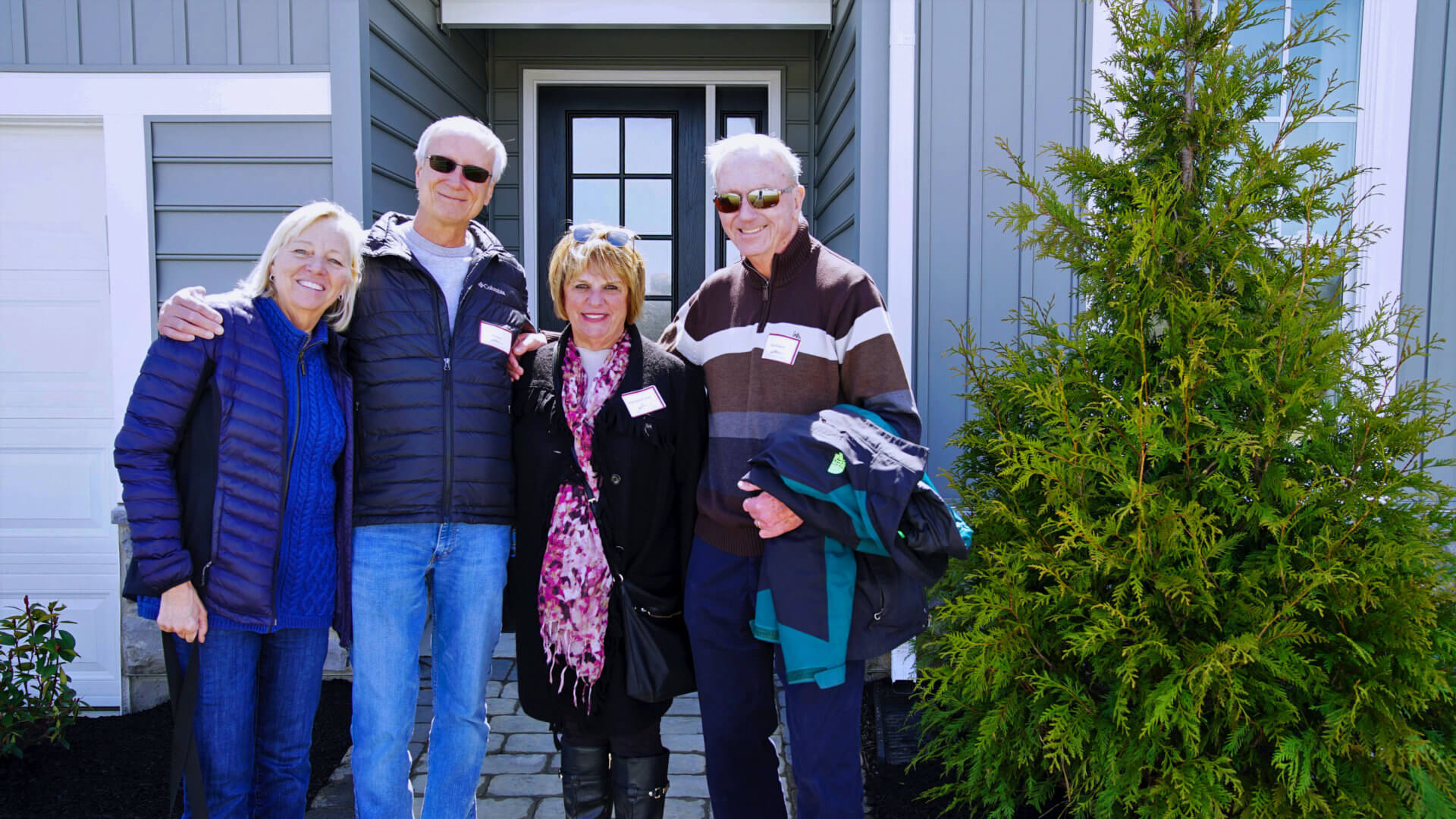 People standing in front of a blue home from Traditions of America