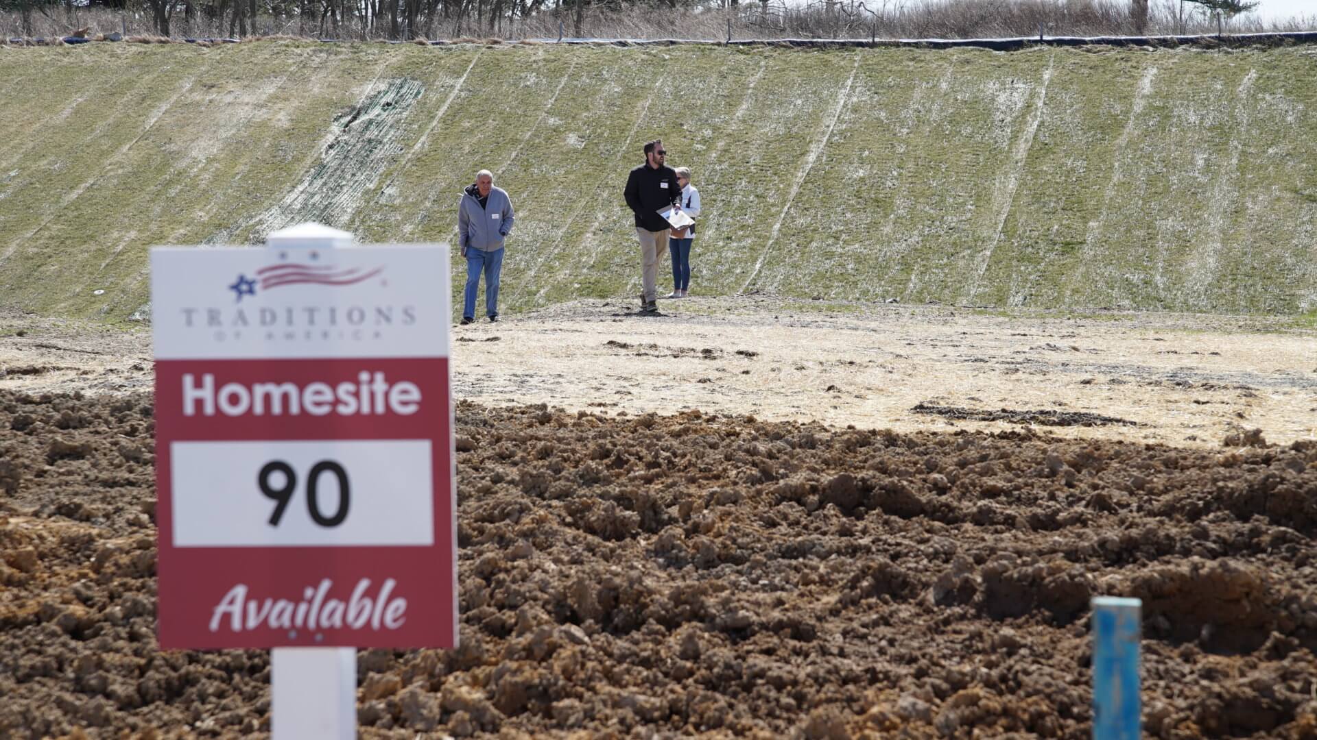 People standing on an empty homesite from Traditions of America