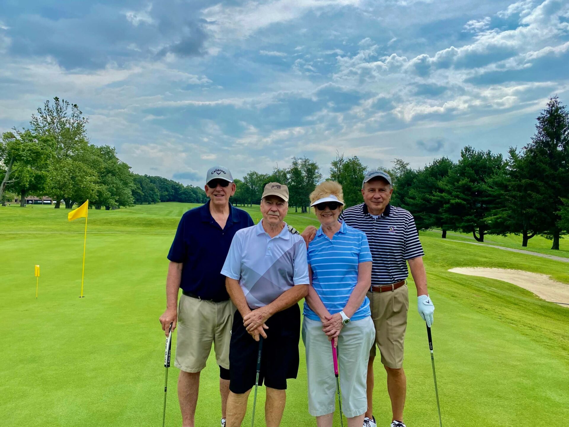 Four people standing on the green of a golf course