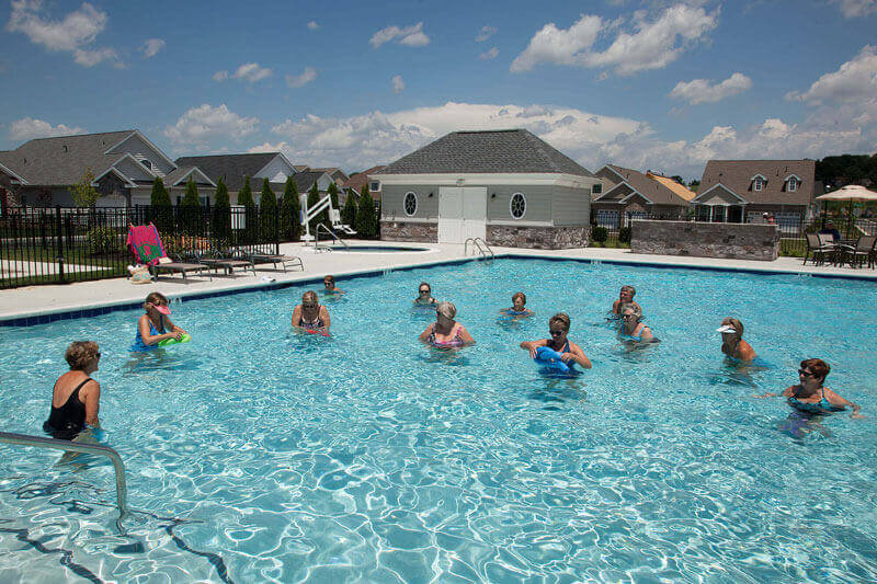 Active adults in the pool at a traditions of America clubhouse