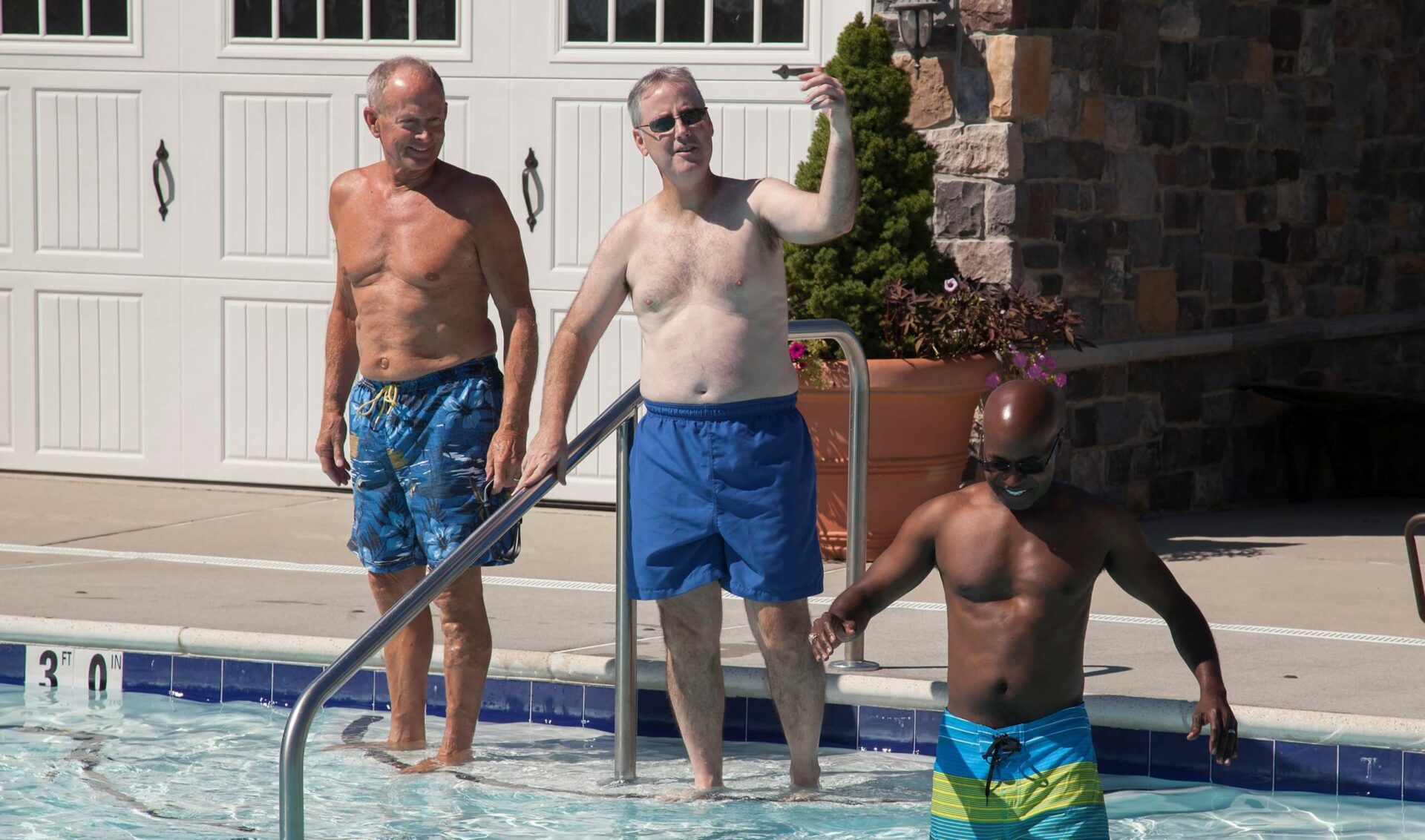 Three men walking into a Traditions of America clubhouse pool