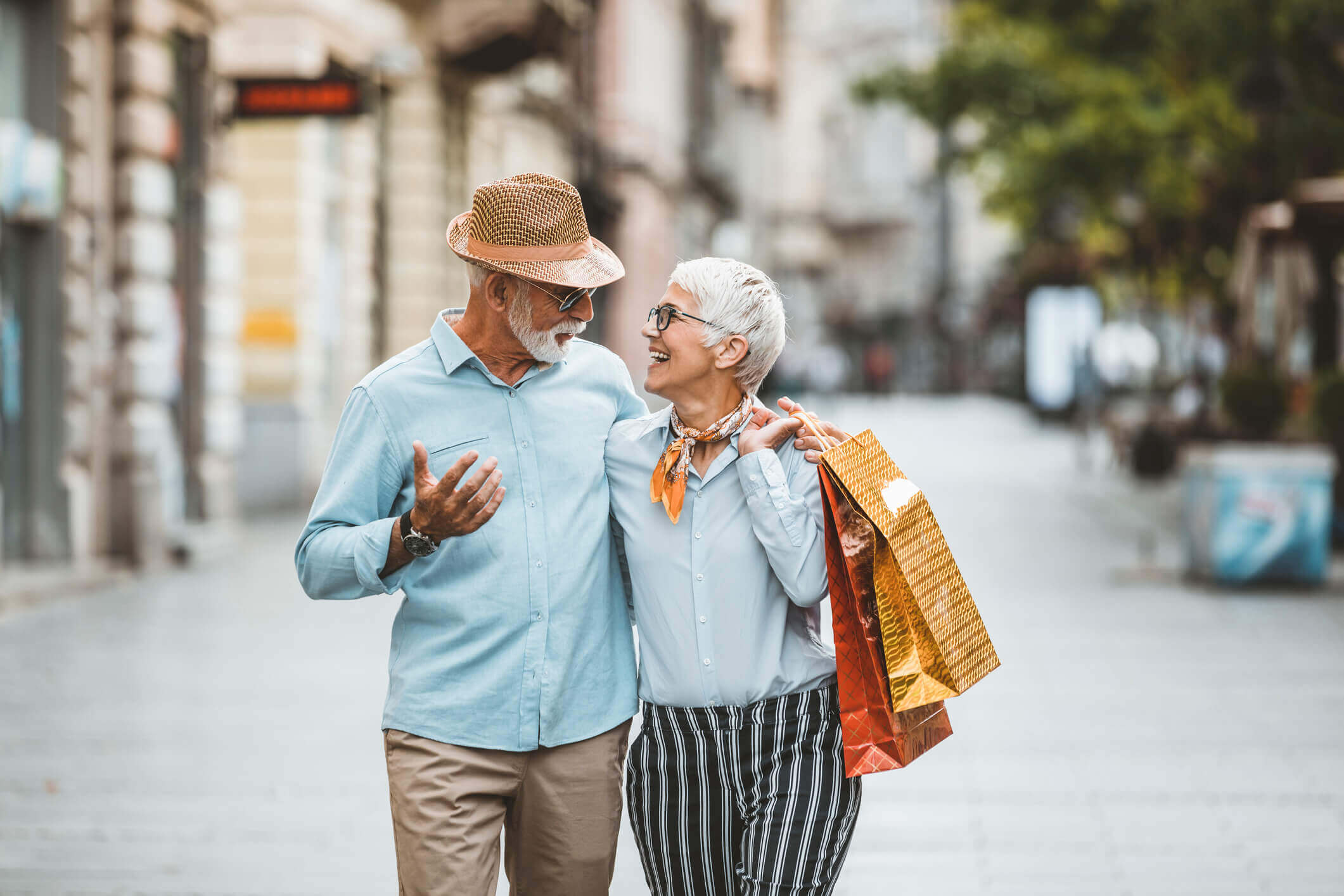 Two active adult people walking through a city with shopping bags