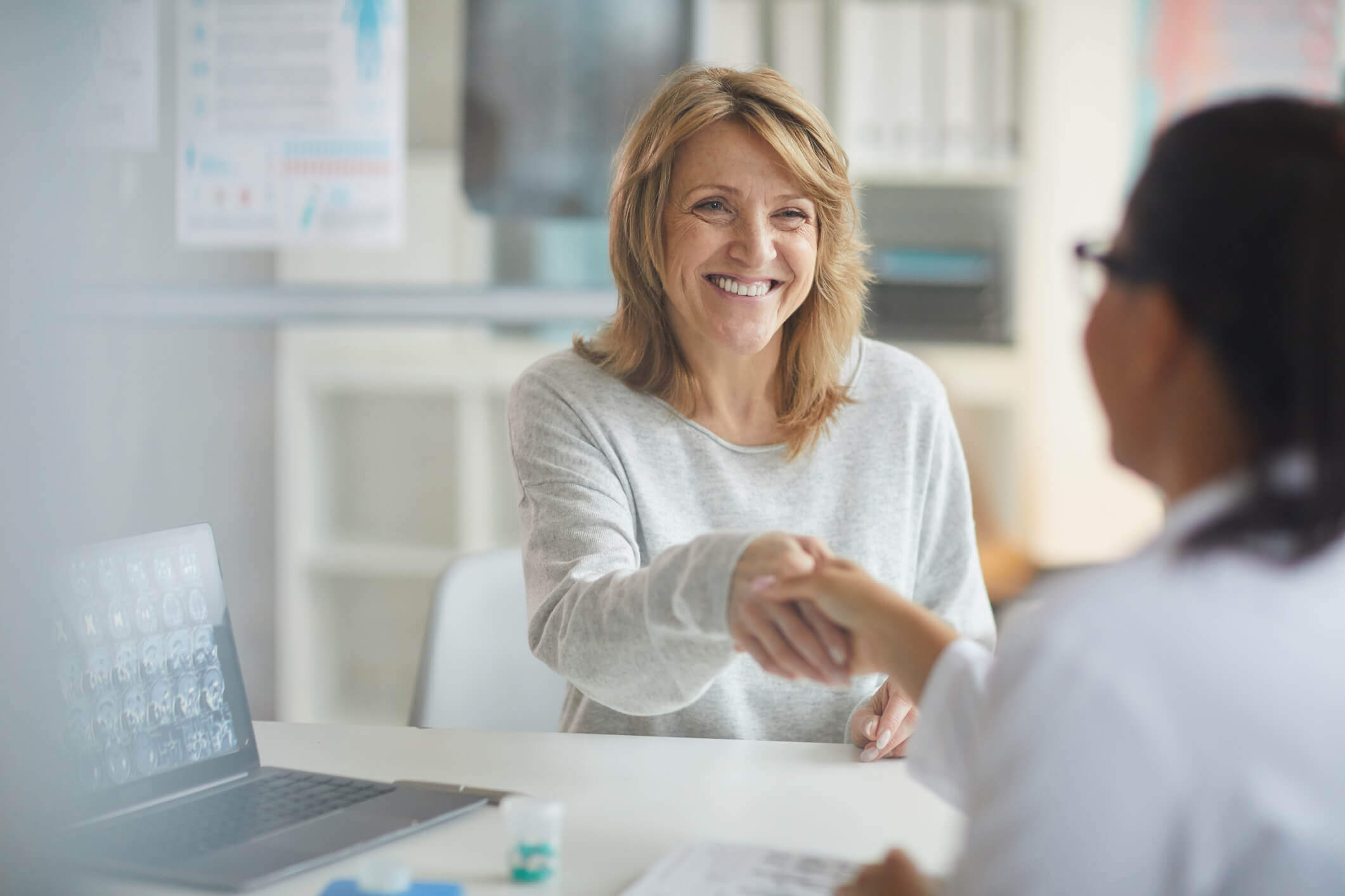 Active adult woman shaking hands with her doctor