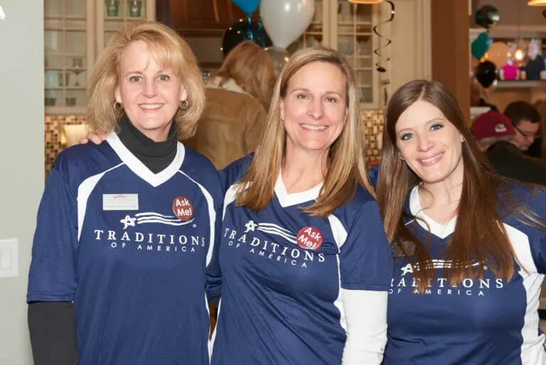 Three employees wearing Traditions of America shirts posing for a photo