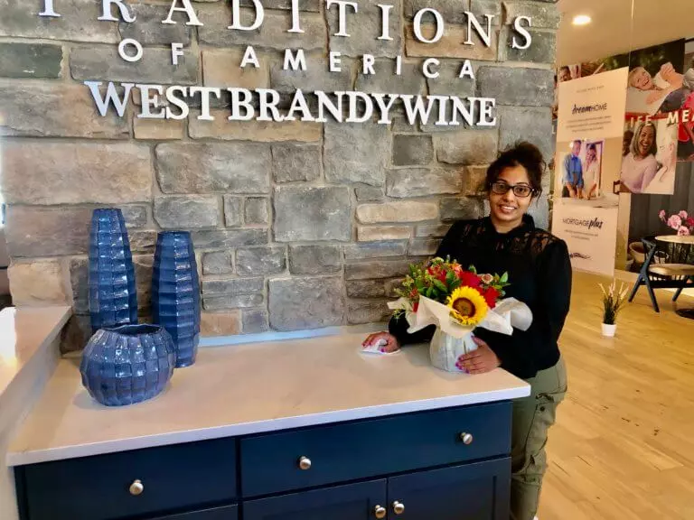Traditions of America Staff Member posing with flowers in the Office