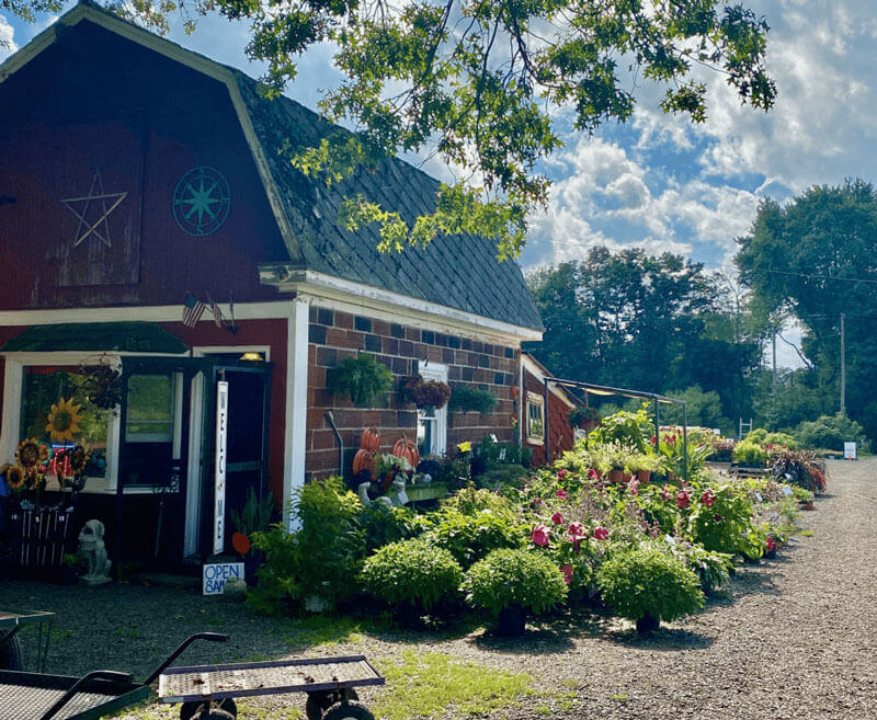 Small Brick shop shaped like a barn with flowers on sale outside